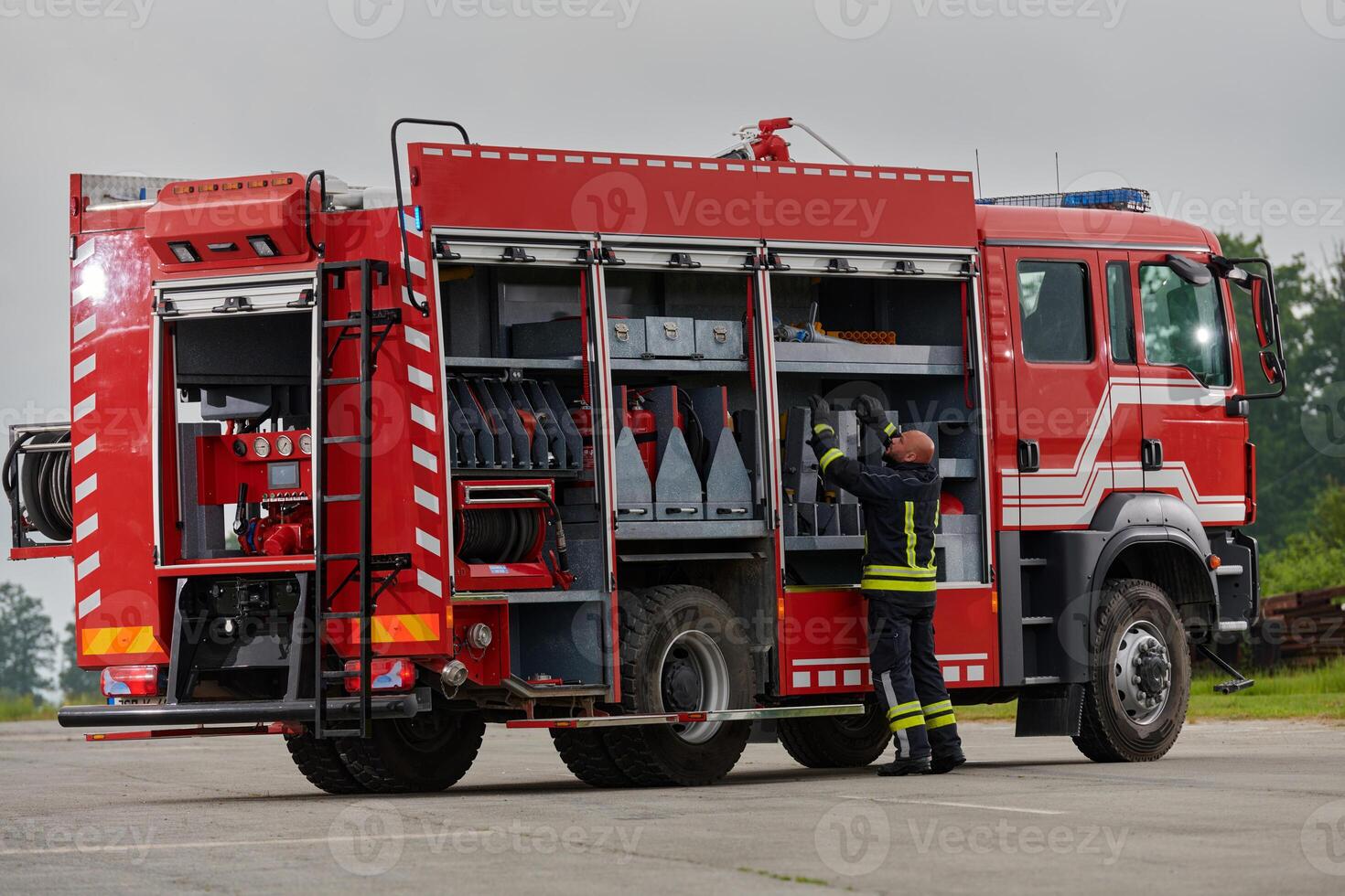 A firefighter meticulously prepares a modern firetruck for a mission to evacuate and respond to dangerous situations, showcasing the utmost dedication to safety and readiness in the face of a fire photo
