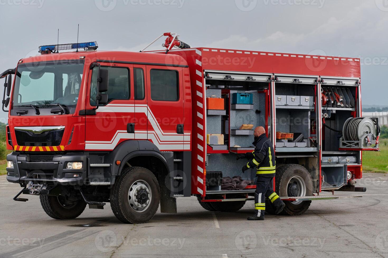 A firefighter meticulously prepares a modern firetruck for a mission to evacuate and respond to dangerous situations, showcasing the utmost dedication to safety and readiness in the face of a fire photo