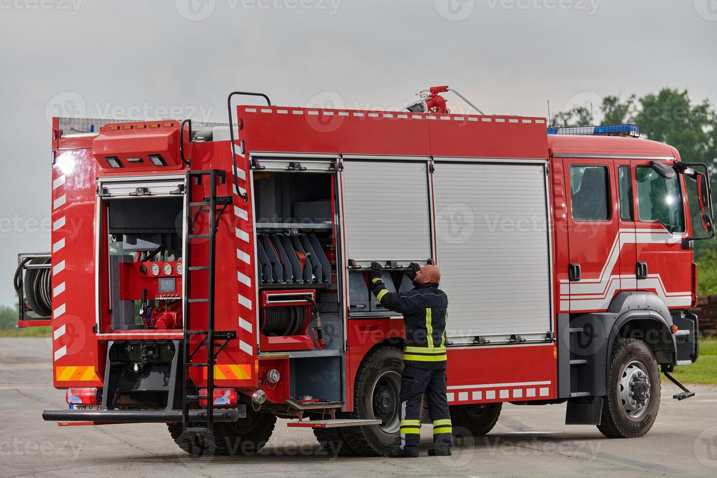 A firefighter meticulously prepares a modern firetruck for a mission to evacuate and respond to dangerous situations, showcasing the utmost dedication to safety and readiness in the face of a fire photo