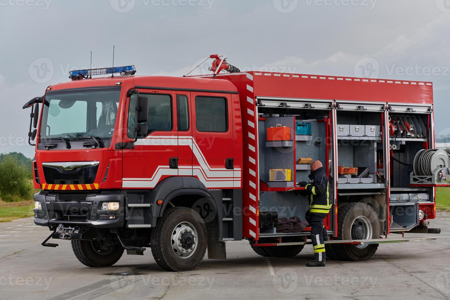 A firefighter meticulously prepares a modern firetruck for a mission to evacuate and respond to dangerous situations, showcasing the utmost dedication to safety and readiness in the face of a fire photo