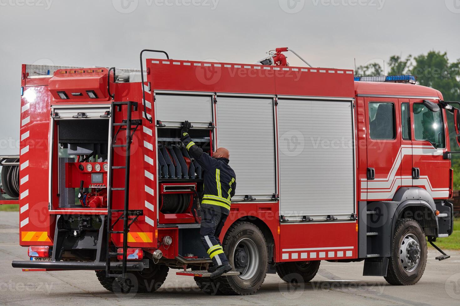 A firefighter meticulously prepares a modern firetruck for a mission to evacuate and respond to dangerous situations, showcasing the utmost dedication to safety and readiness in the face of a fire photo