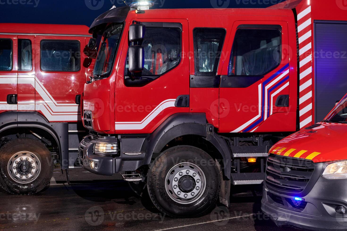 A pair of highly modern and quality fire trucks illuminate the night with their rotating lights, symbolizing the cutting-edge technology and preparedness of the firefighting fleet, ready to respond to photo