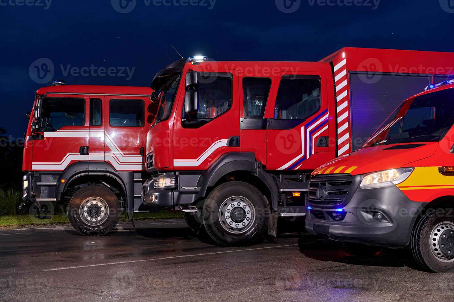 A pair of highly modern and quality fire trucks illuminate the night with their rotating lights, symbolizing the cutting-edge technology and preparedness of the firefighting fleet, ready to respond to photo