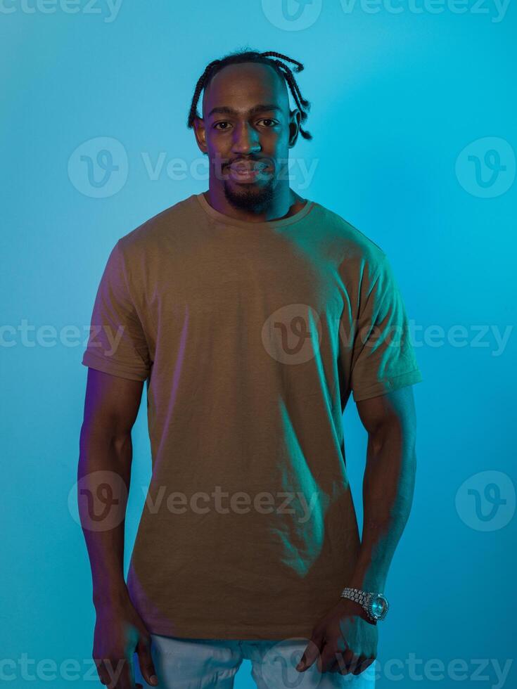 African American man with a modern and sophisticated hairstyle stands confidently against a vibrant blue backdrop, showcasing a blend of contemporary fashion and cultural identity with elegance and photo