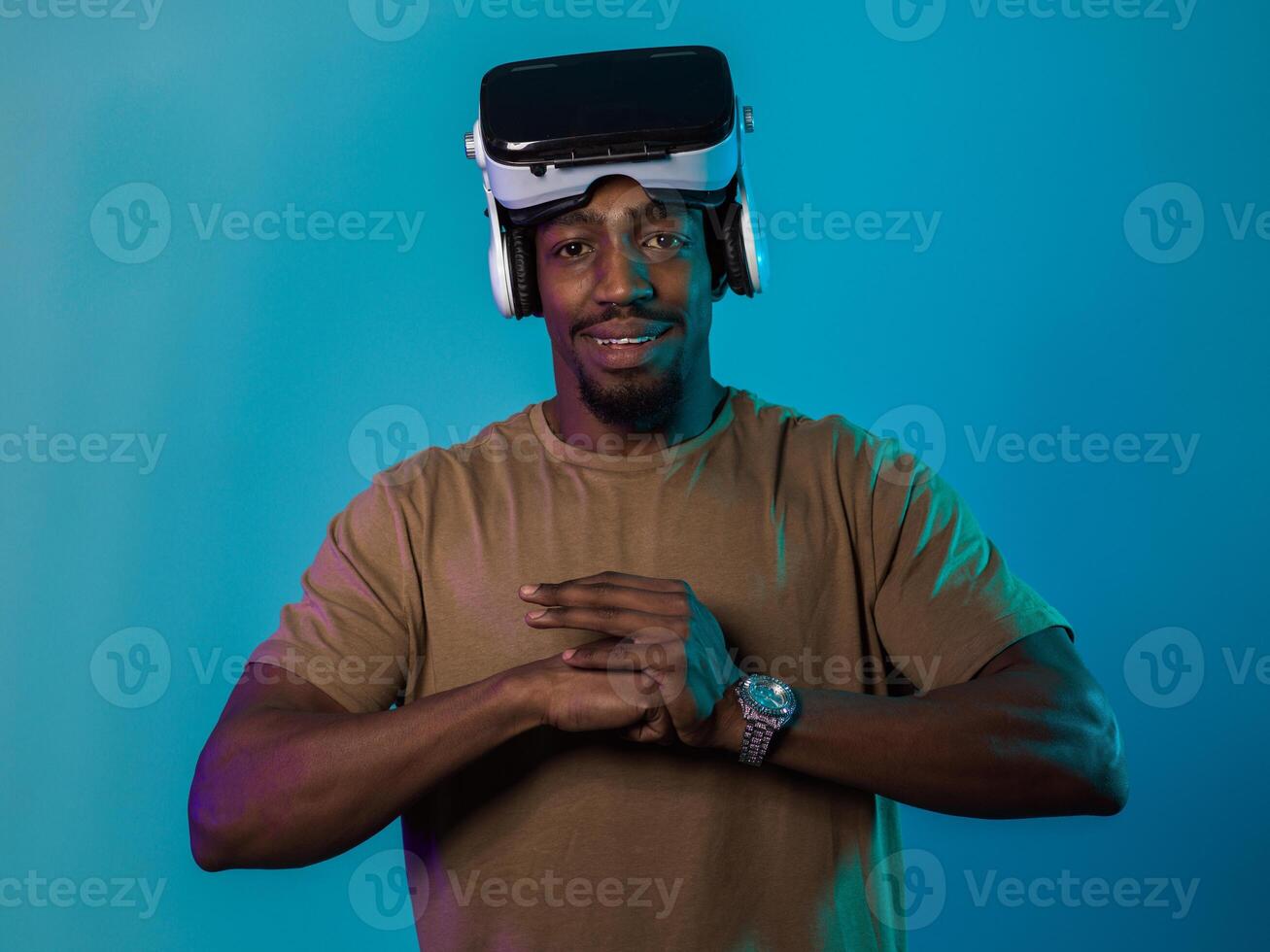 In an avant-garde scene, an African American man engages in cutting-edge virtual reality gaming, utilizing VR glasses to immerse himself in futuristic boxing games, set against a vivid blue background photo