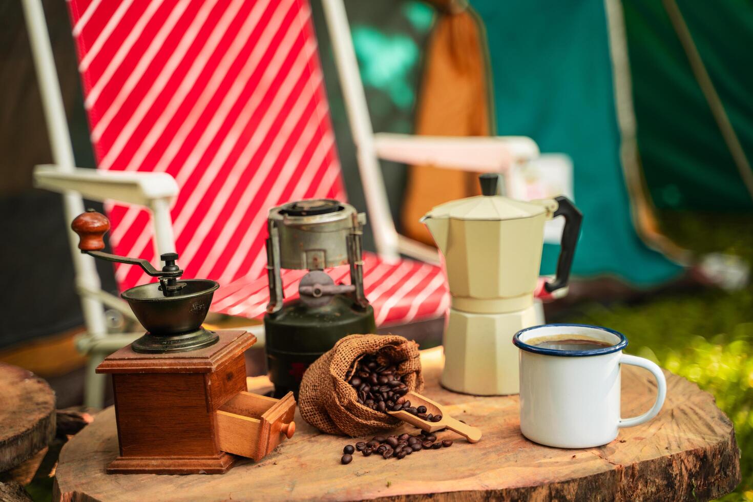 selective focus of vintage coffee set on the old wooden table In front of the retro cabin tent, Antique oil lamp, retro chairs, Group of camping tents, and soft focus. photo