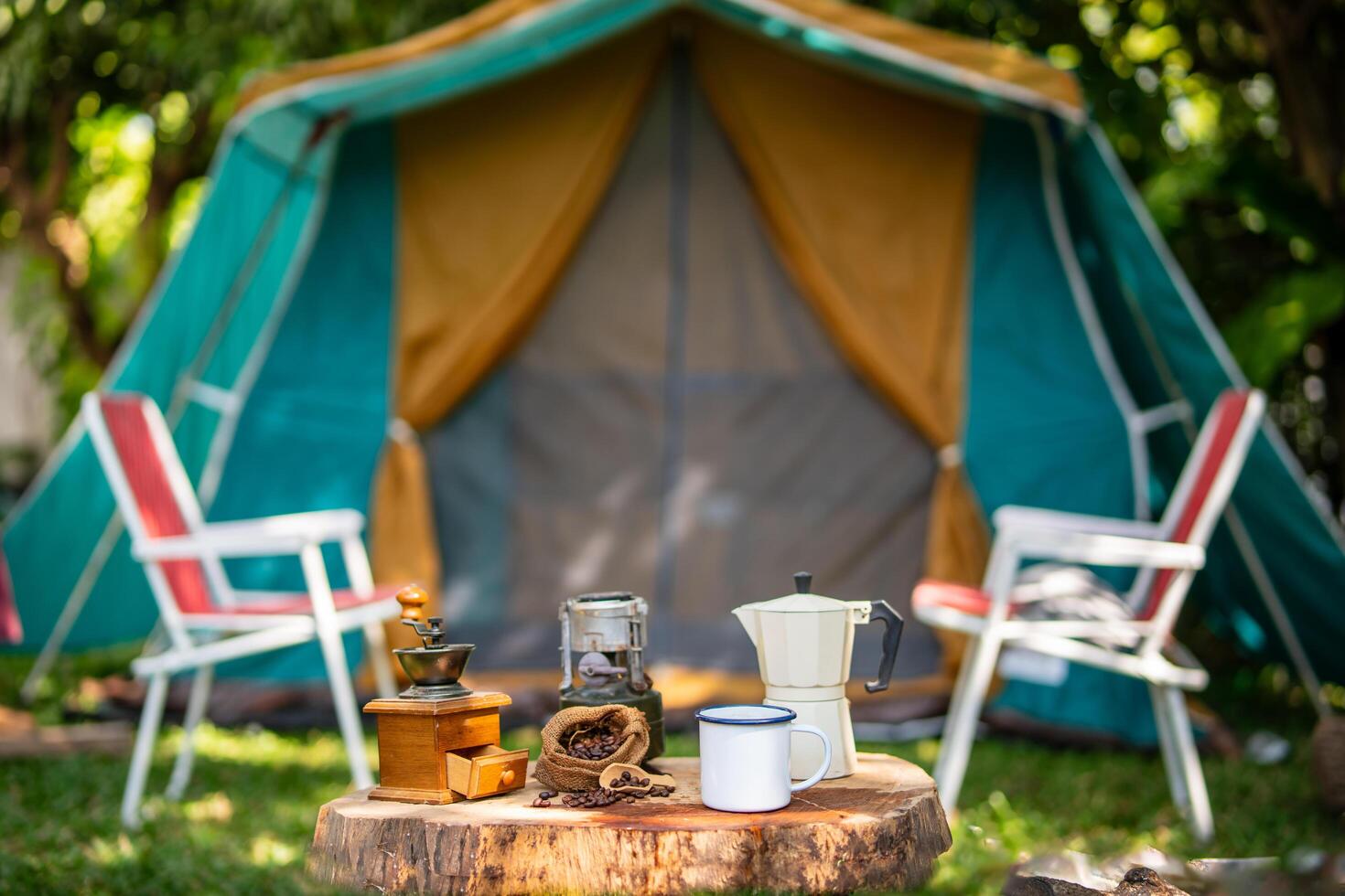 selective focus of vintage coffee set on the old wooden table In front of the retro cabin tent, retro chairs, Group of camping tents, and soft focus. photo