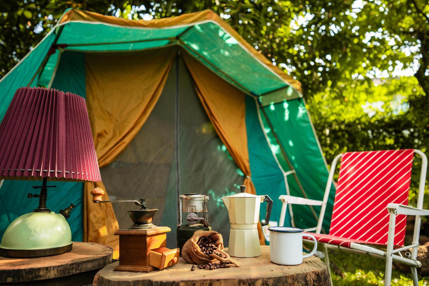 selective focus of vintage coffee set on the old wooden table In front of the retro cabin tent, Antique oil lamp, retro chairs, Group of camping tents, and soft focus. photo