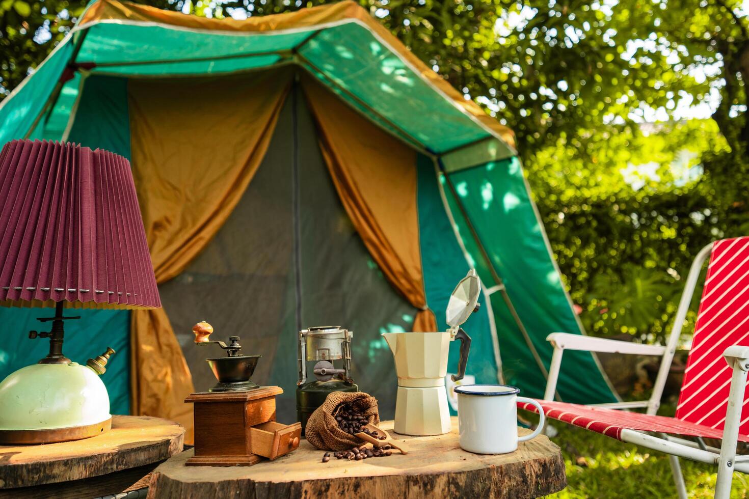 selective focus of vintage coffee set on the old wooden table In front of the retro cabin tent, Antique oil lamp, retro chairs, Group of camping tents, and soft focus. photo