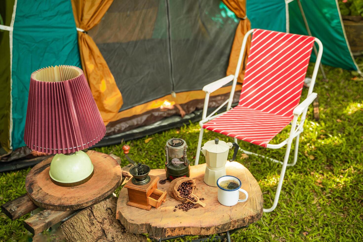 selective focus of vintage coffee set on the old wooden table In front of the retro cabin tent, Antique oil lamp, retro chairs, Group of camping tents, and soft focus. photo