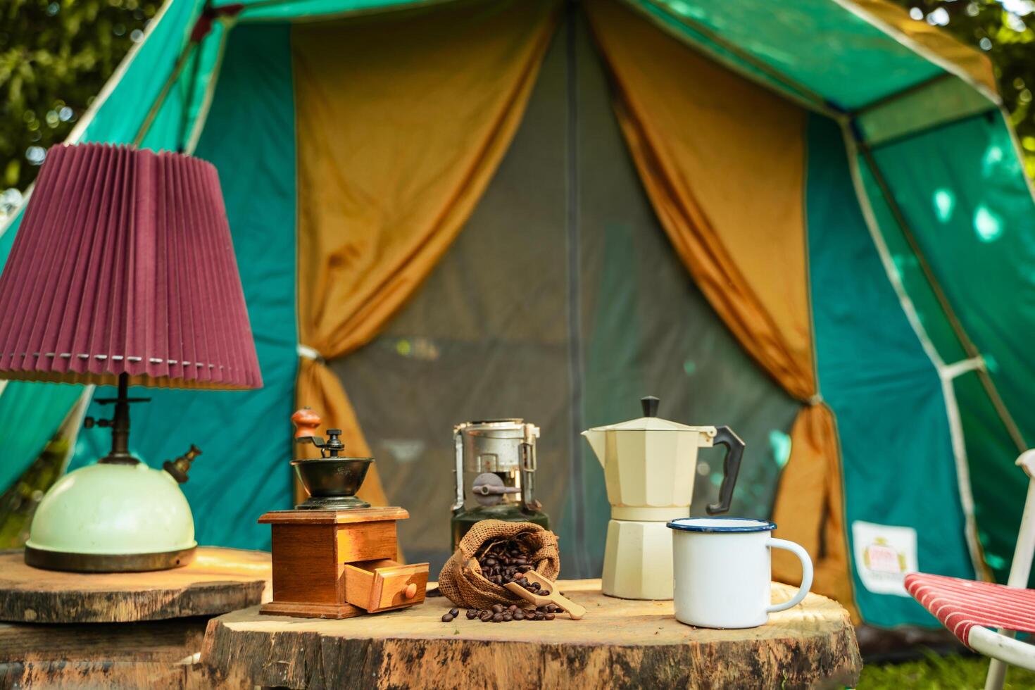 selective focus of vintage coffee set on the old wooden table In front of the retro cabin tent, Antique oil lamp, retro chairs, Group of camping tents, and soft focus. photo
