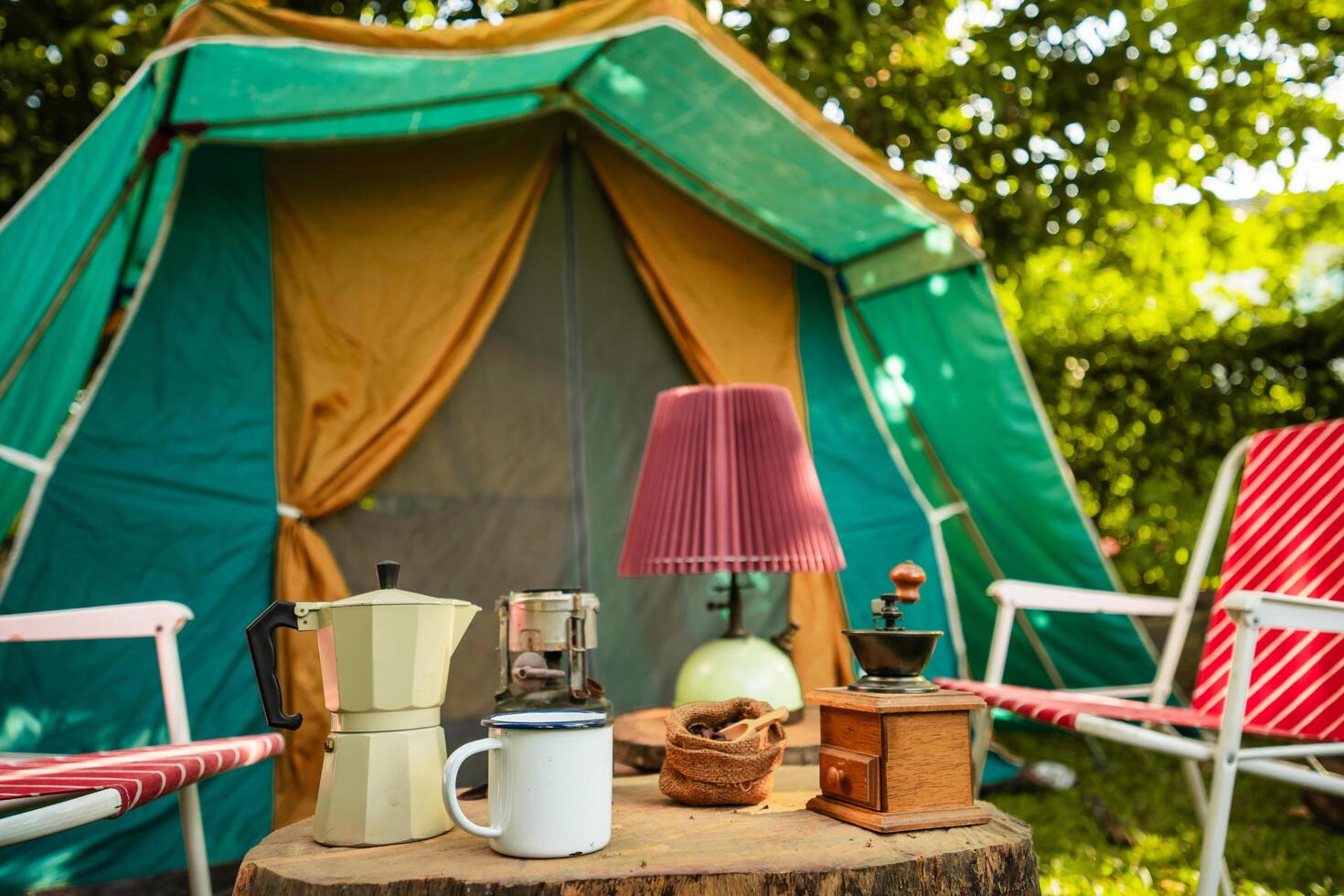selective focus of vintage coffee set on the old wooden table In front of the retro cabin tent, Antique oil lamp, retro chairs, Group of camping tents, and soft focus. photo