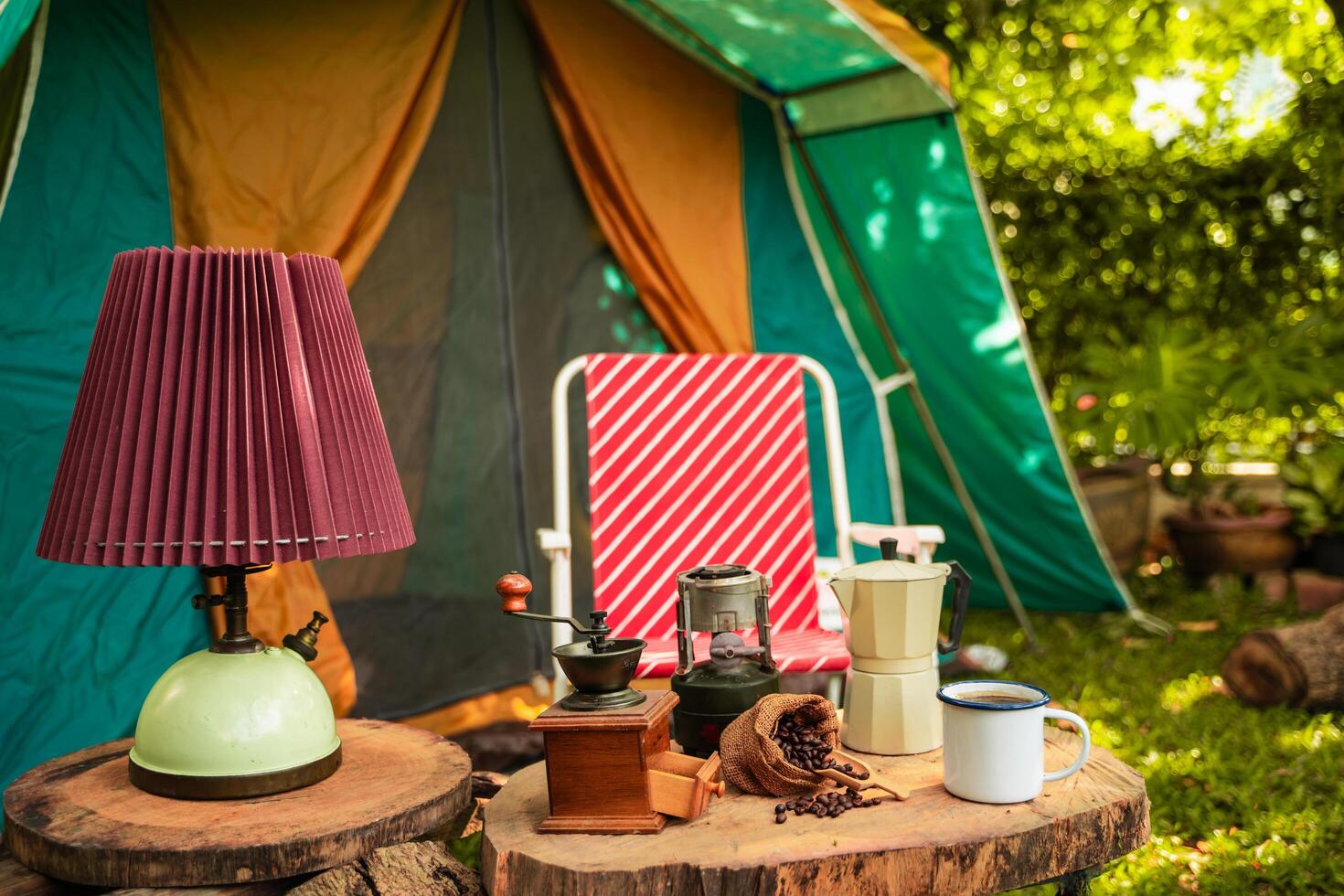 selective focus of vintage coffee set on the old wooden table In front of the retro cabin tent, Antique oil lamp, retro chairs, Group of camping tents, and soft focus. photo