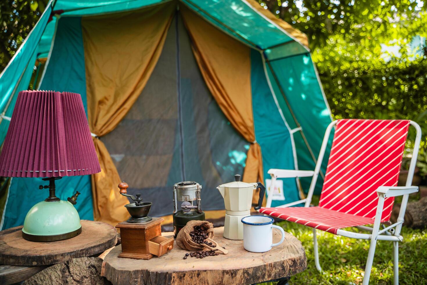 selective focus of vintage coffee set on the old wooden table In front of the retro cabin tent, Antique oil lamp, retro chairs, Group of camping tents, and soft focus. photo