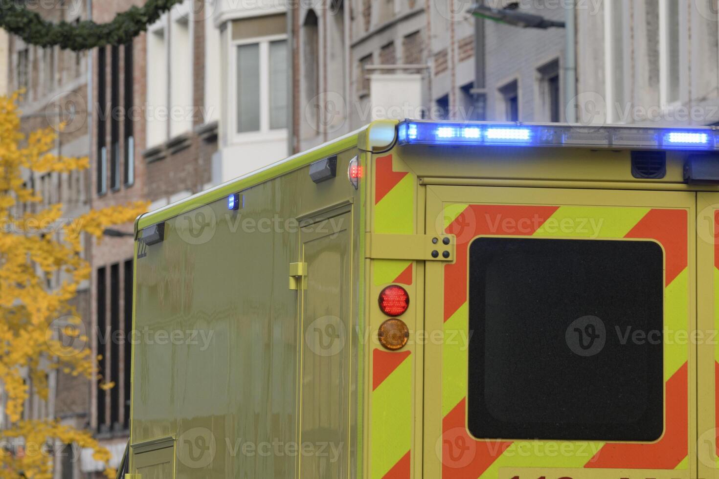 An ambulance on a city street, a fragment of the corps with the light signal on. photo