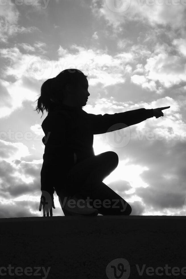 Silhouette profile of a girl 8-10 years old on a hill, against a background of a stormy sky. black and white image photo