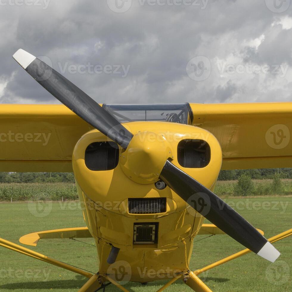 Front part of a light aircraft, yellow surface with a propeller. Square fomat. Close-up, screws, texture photo