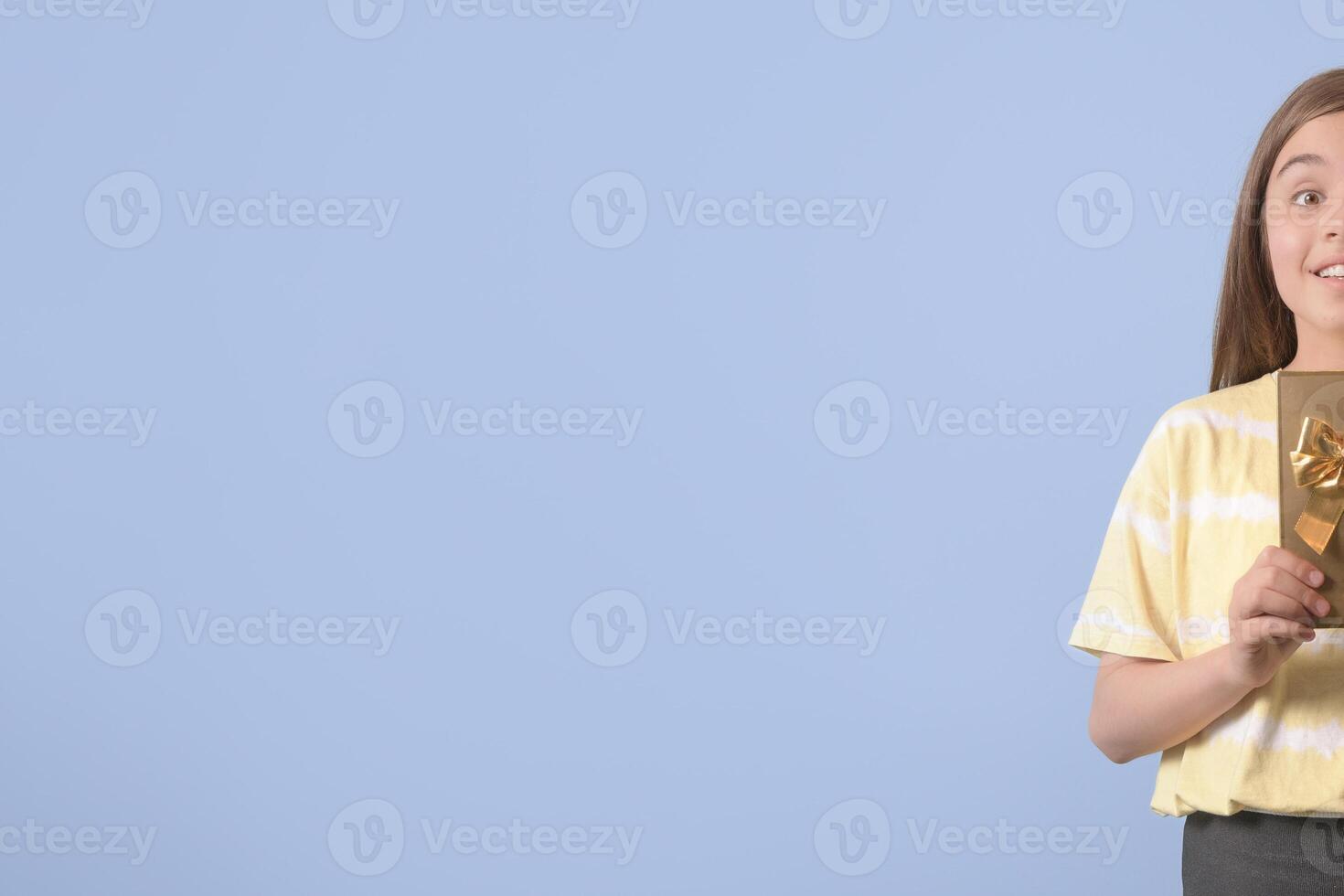 I have something for you. A teenage girl holds a gift in a gilded package with a bow. Place for text photo