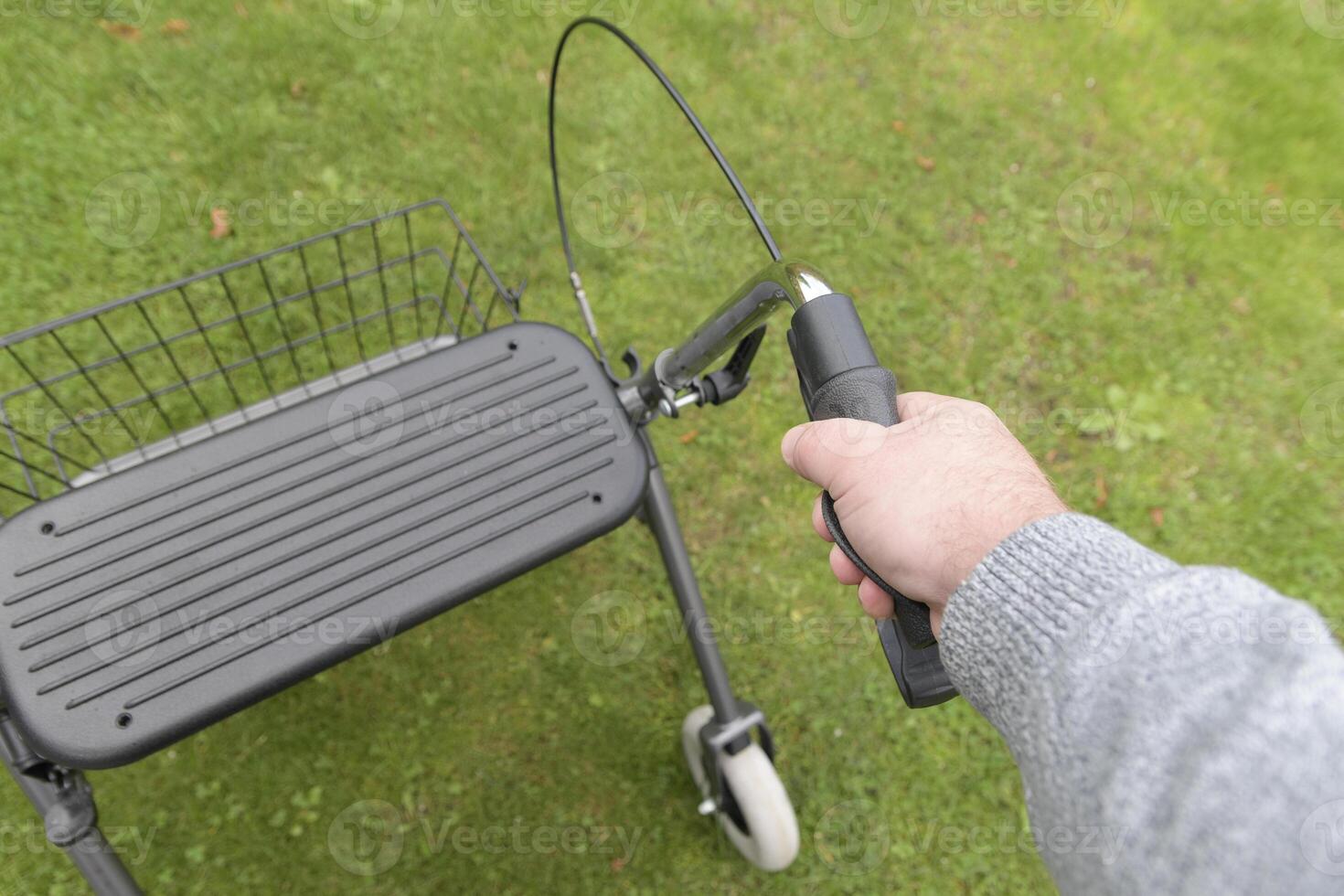 A man holding on to the left handle of a rollator. Using Walker Rollator view from above. photo