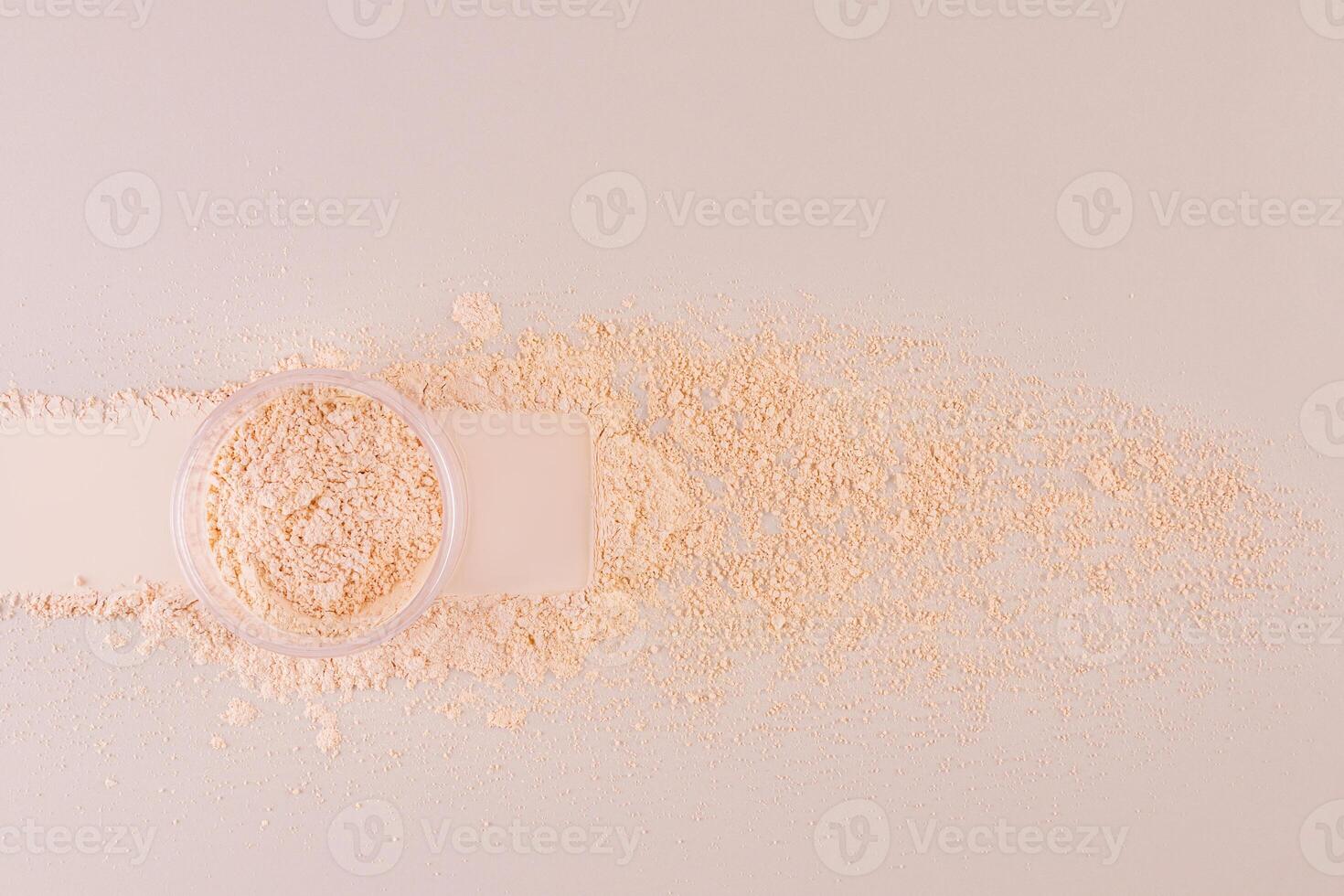 A cosmetic jar with loose powder in a beige tone stands on the sample with a trace of a jar and a background of loose powder. decorative cosmetics photo