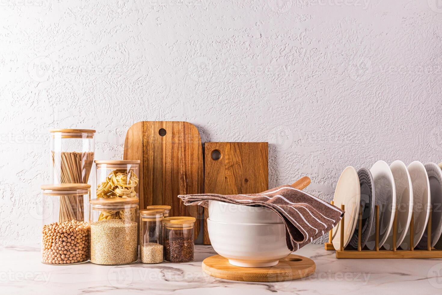 A beautiful kitchen background with a storage area for bulk products in glass jars, plates in the dryer, a large bowl on a marble countertop. photo