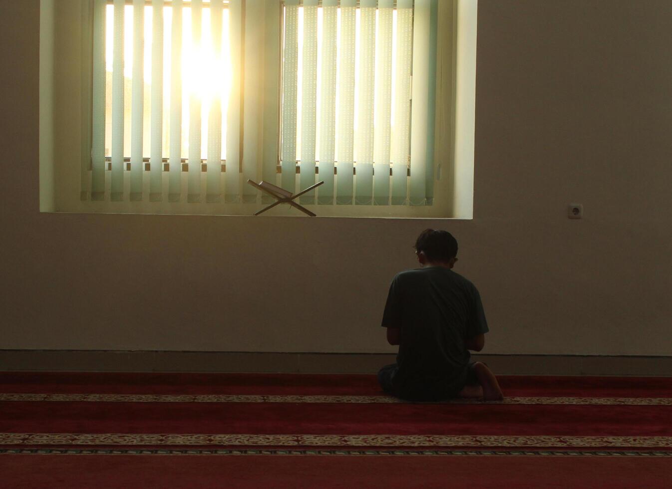 portrait from behind of a Muslim praying in the mosque, giving thanks to Allah SWT. In Islamic spiritual belief to worship God. photo