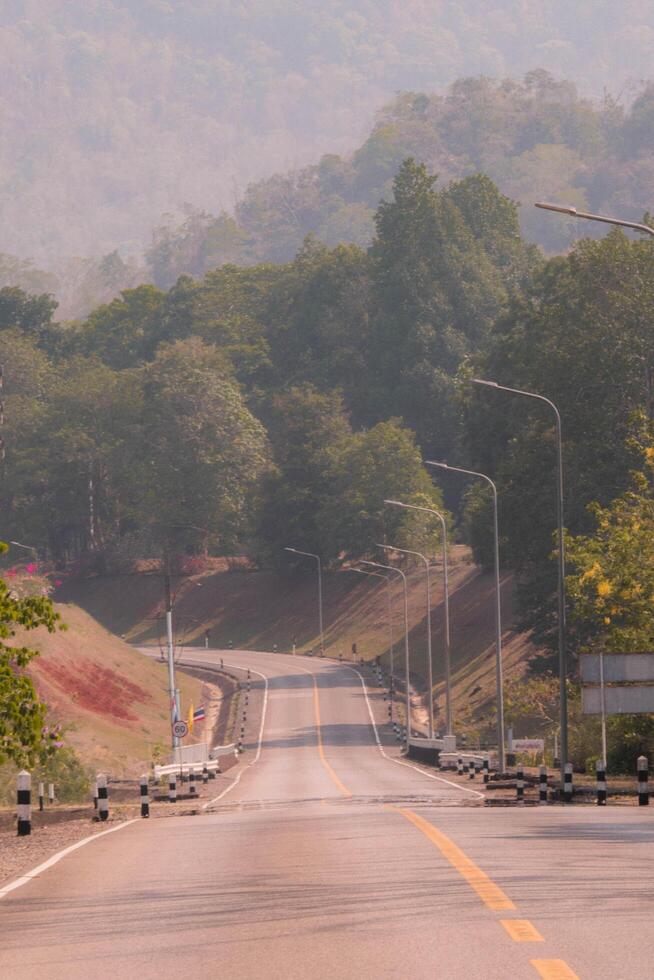 The scene of the road at the dam, with the mountains in the background and a light pole. photo