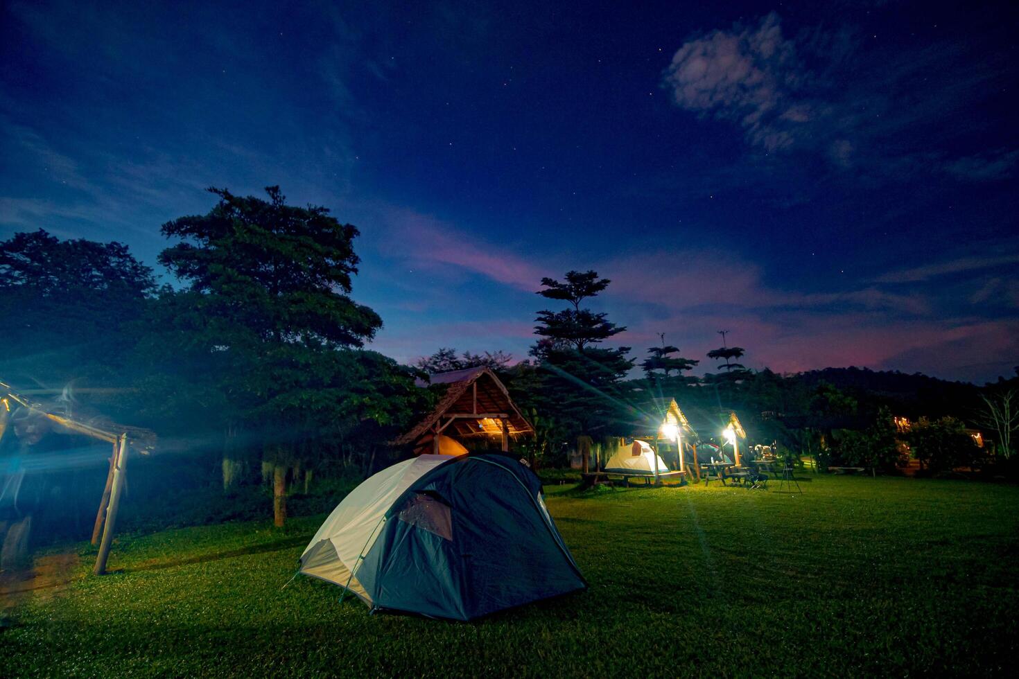 A tent set up for a night of camping in a forest, surrounded by nature and trees under the starry sky. photo