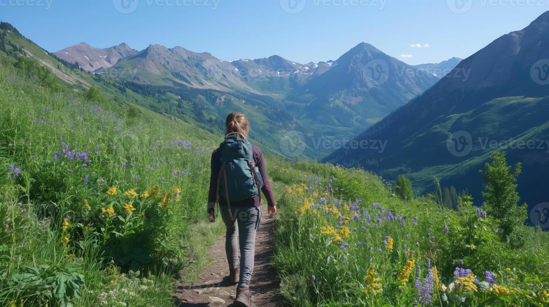 A woman with a backpack walking on a trail in the mountains photo