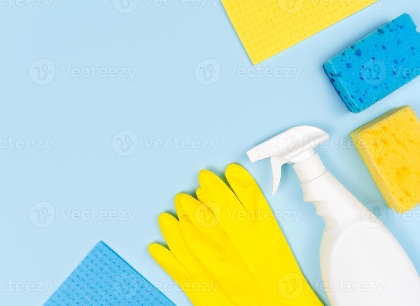 Cleaning product, rubber gloves and cleaning sponges on a blue background. Cleaning concept. Top view. Copy space. photo