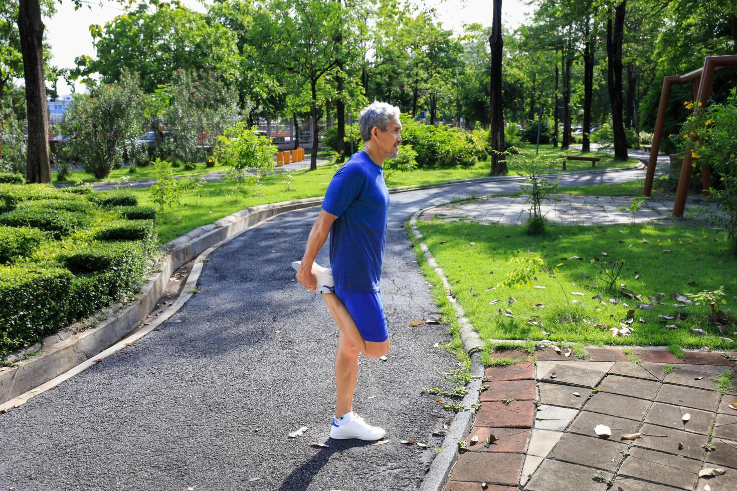 Senior Asian man is stretching his leg muscle during warm up exercise work out in the morning at public park for healthy and longevity concept photo
