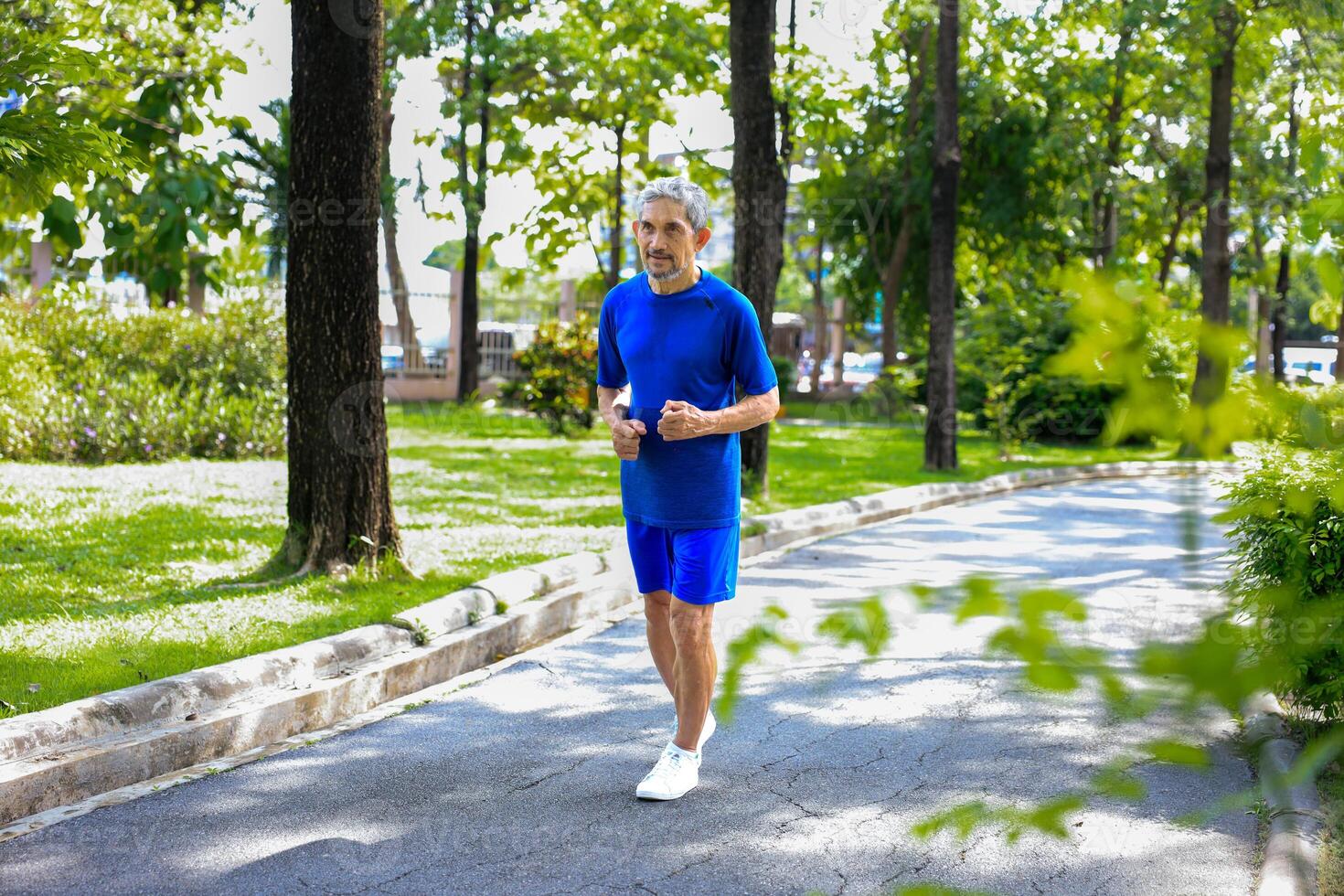 Senior Asian man is doing running exercise work out in the morning at public park for healthy and longevity concept photo