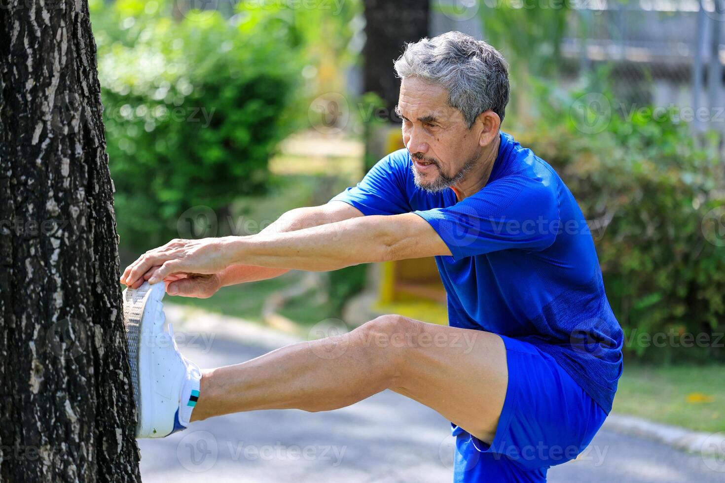 Senior Asian man is stretching his leg muscle during warm up exercise work out in the morning at public park for healthy and longevity photo