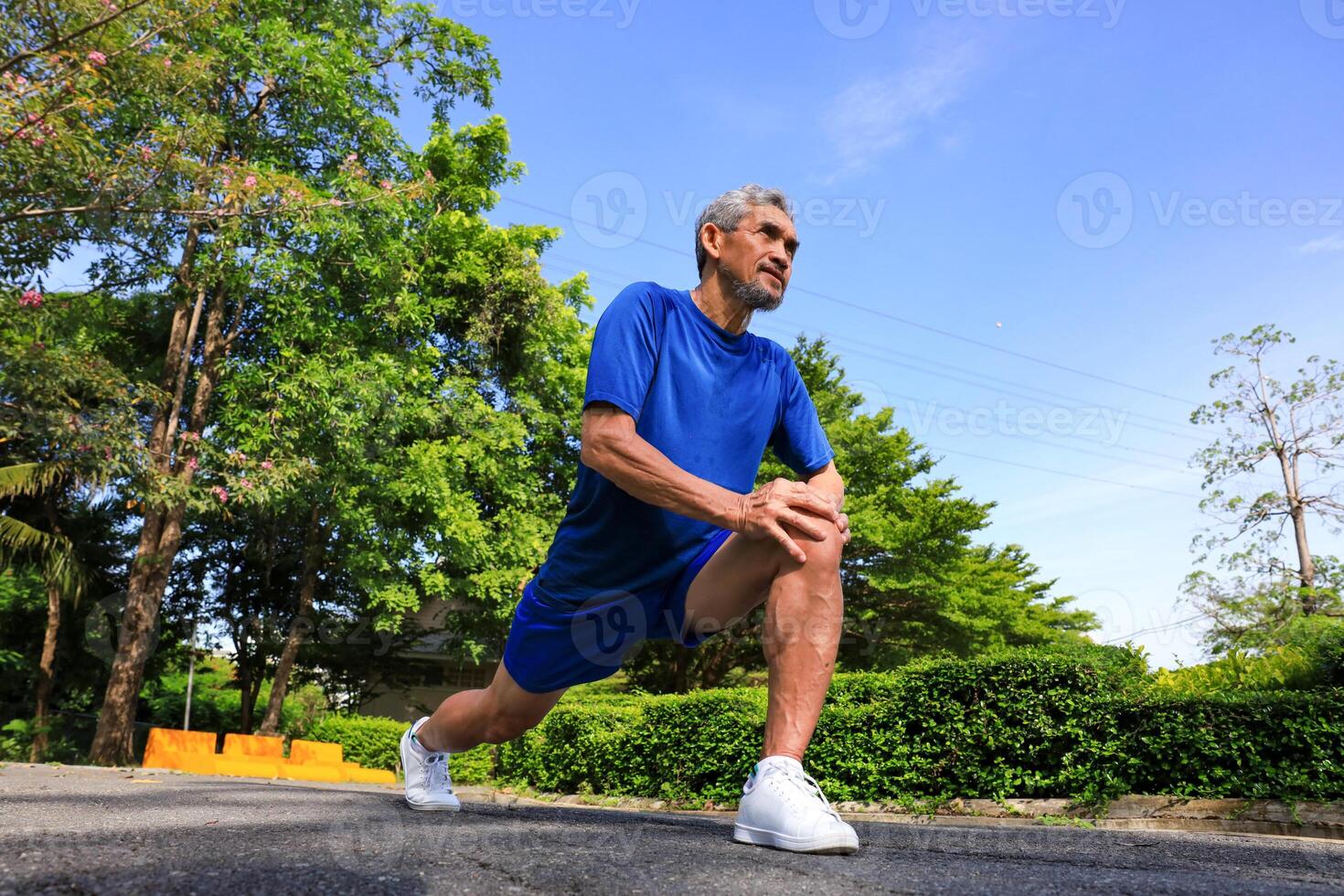 Senior Asian man is stretching his leg muscle during warm up exercise work out in the morning at public park for healthy and longevity photo