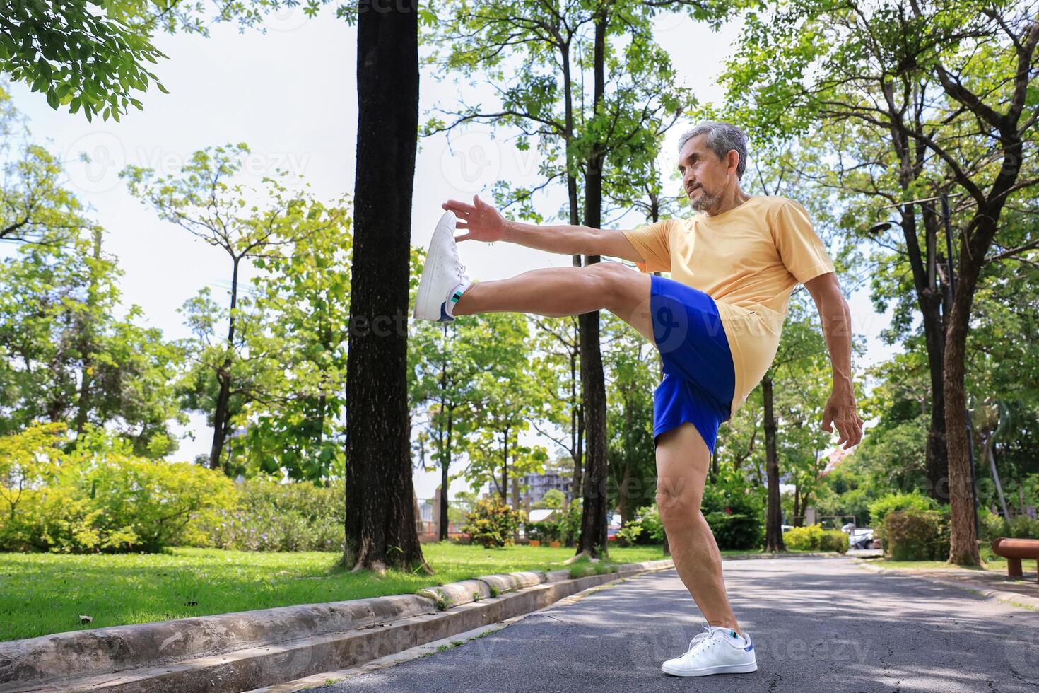 Senior Asian man is stretching his leg muscle during warm up exercise work out in the morning at public park for healthy and longevity photo