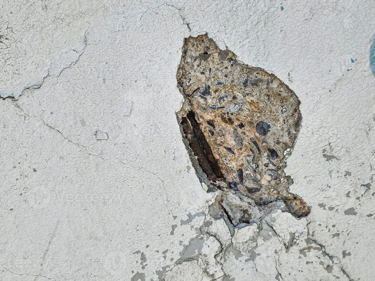 closeup view of a concrete surface with a large, Revealing the steel structure inside photo