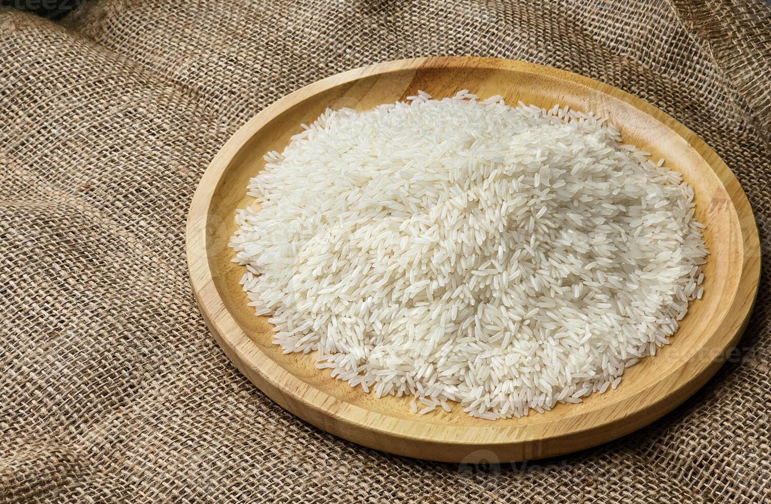 Side view, rice grains on a wooden plate. sackcloth background photo