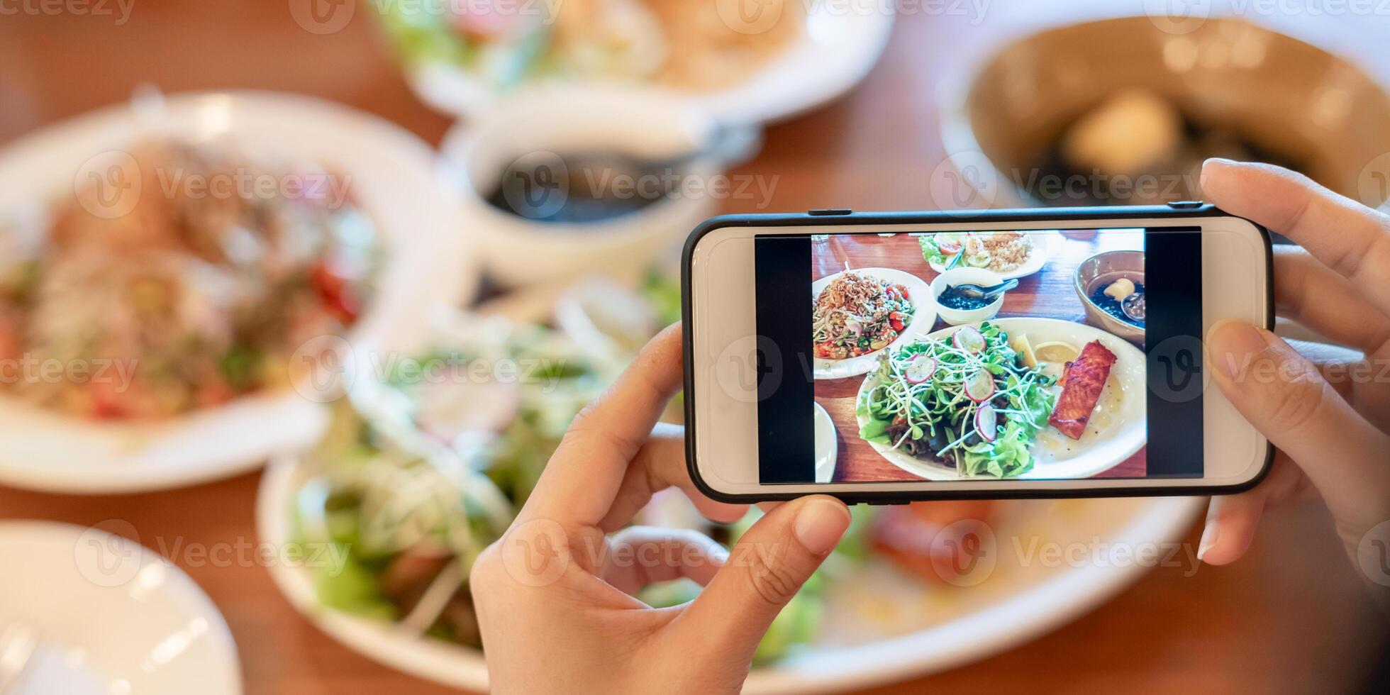 restaurant owner takes a picture of the food on the table with a smartphone to post on a website. Online food delivery, ordering service, influencer, review, social media, share, marketing, interest. photo