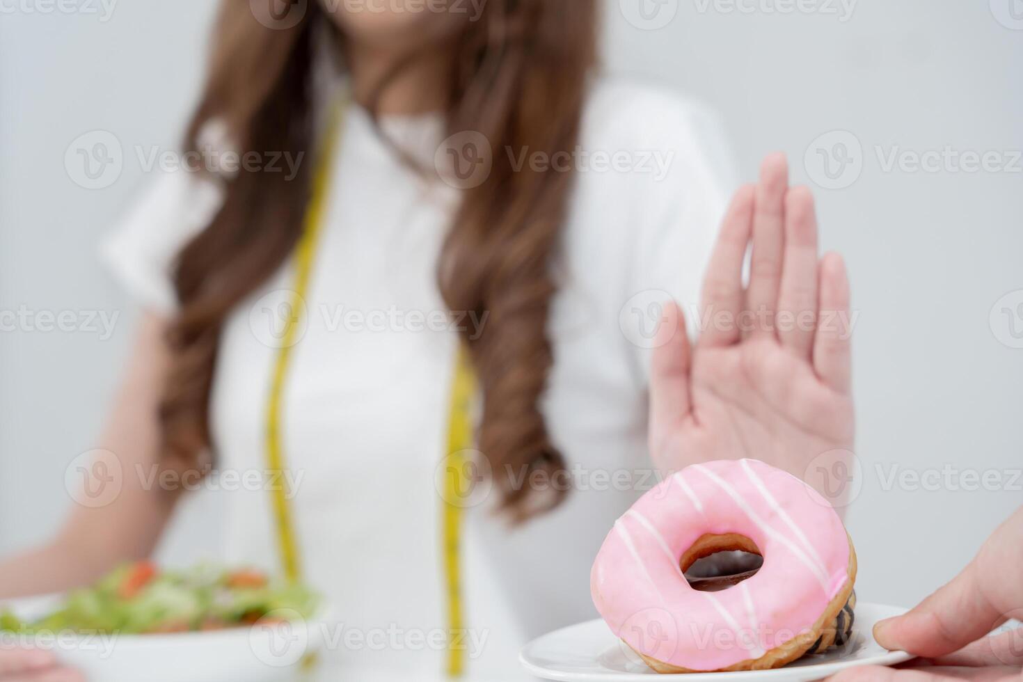 Diet and dieting. Beauty slim female body confuse donut. Woman in exercise clothes achieves weight loss goal for healthy life, crazy about thinness, thin waist, nutritionist. photo