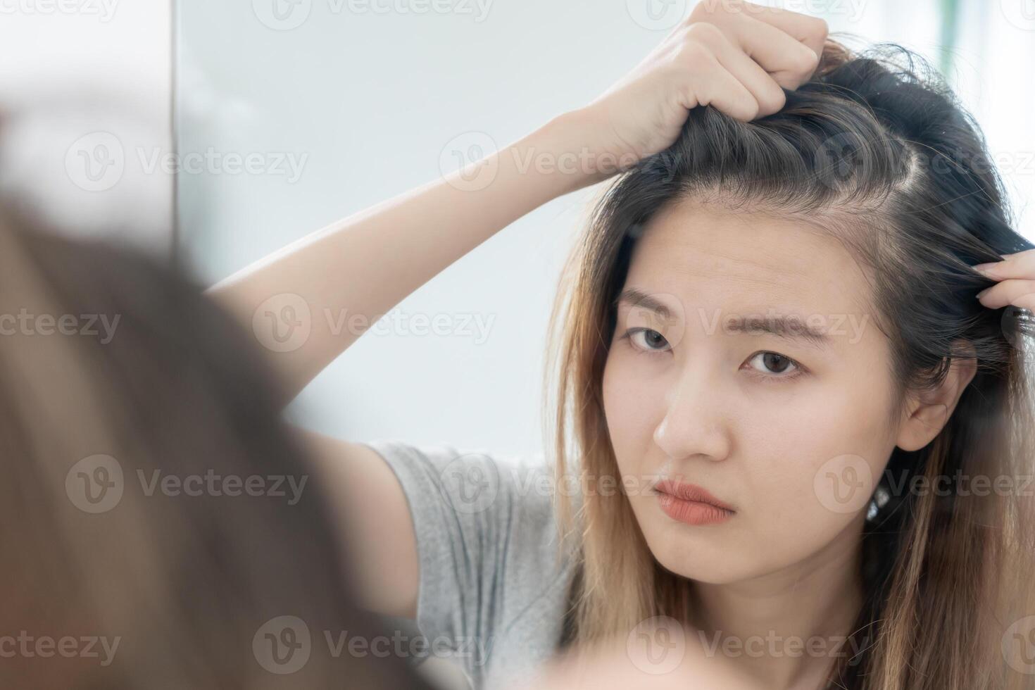 Asian woman very sad and upset looking at damaged hair, hair loss, hair thinning problem, vitamin deficiency, baldness, postpartum, biotin, zinc, menstrual or endocrine disorders, hormonal imbalance photo