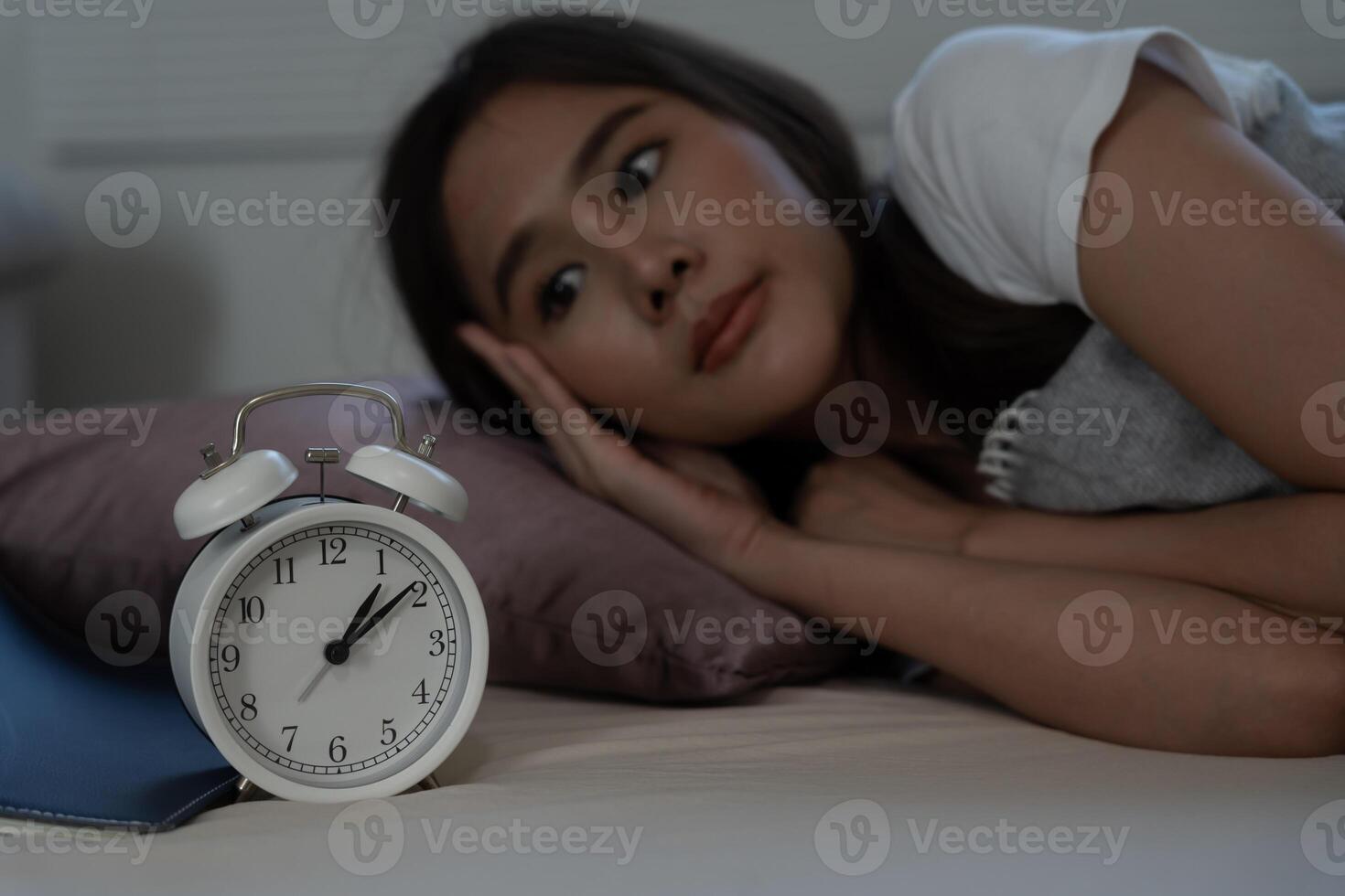 asian woman in bed late trying to sleep suffering insomnia, sleepless or scared in a nightmare, looking sad worried and stressed. Tired and headache or migraine waking up in the middle of the night. photo