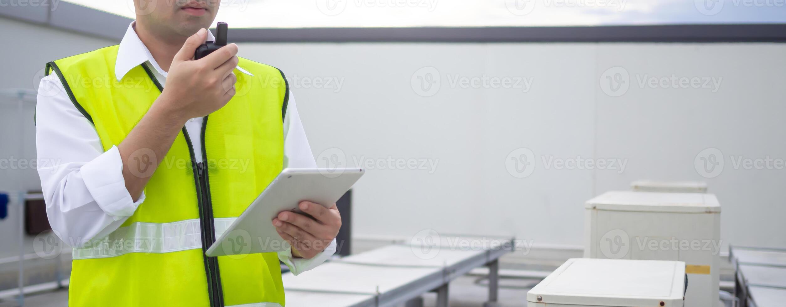 Asian maintenance engineer work on the roof of factory. contractor inspect compressor system and plans installation of air condition systems in construction. technology, walky talky, maintenance photo