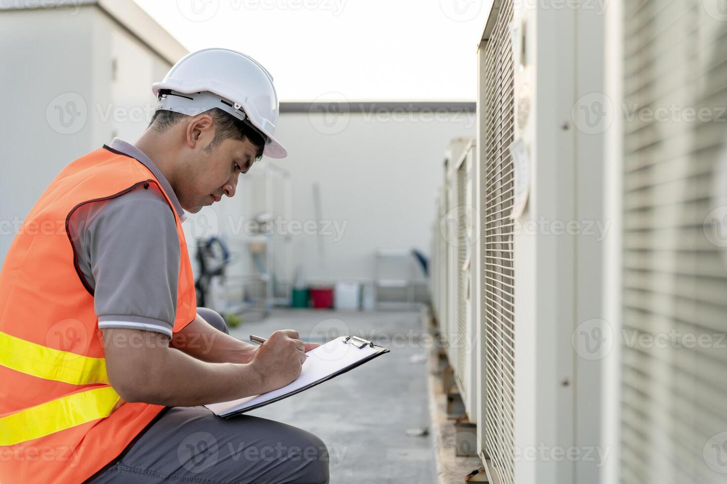 Asian maintenance engineer works on the roof of factory. contractor inspect compressor system and plans installation of air condition systems in construction. Checklist, inspector, control photo
