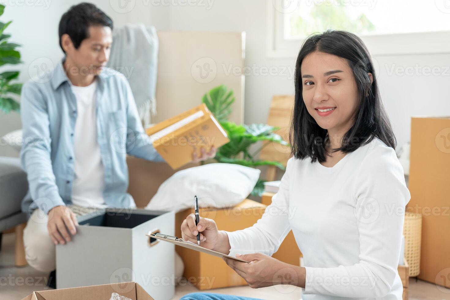 Move house, relocation. wife and husband record quantity furniture for new apartment, Inside the room are cardboard boxes containing personal belongings. Move into a house or condominium photo