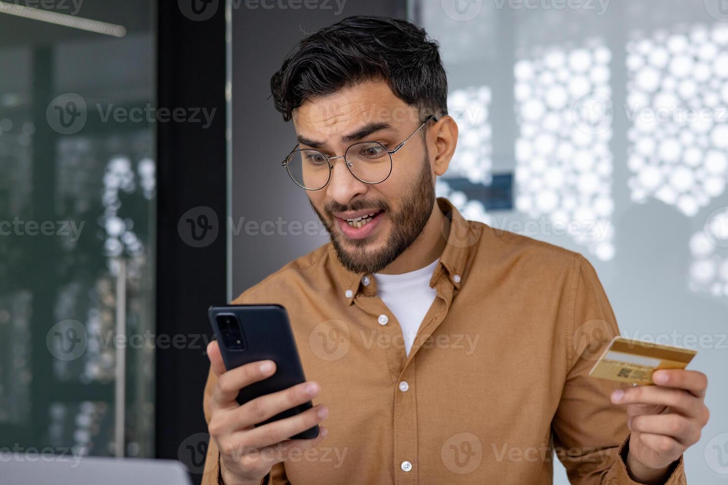 Man experiencing frustration while checking credit card transaction on smartphone. Concept of online shopping, financial problem, or fraud. photo