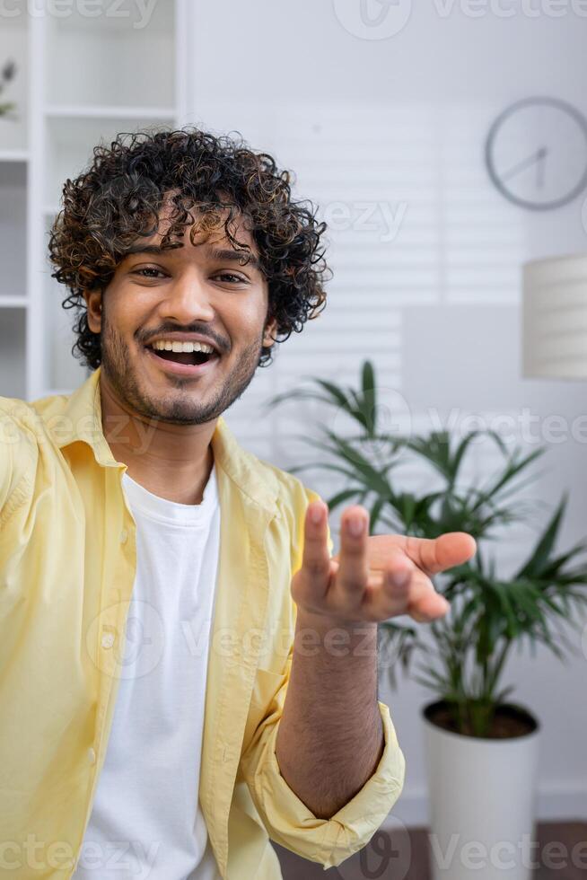 Smiling man making a call from home, joyfully engaging in conversation. Indoor setting with plants and a clock in the background. photo