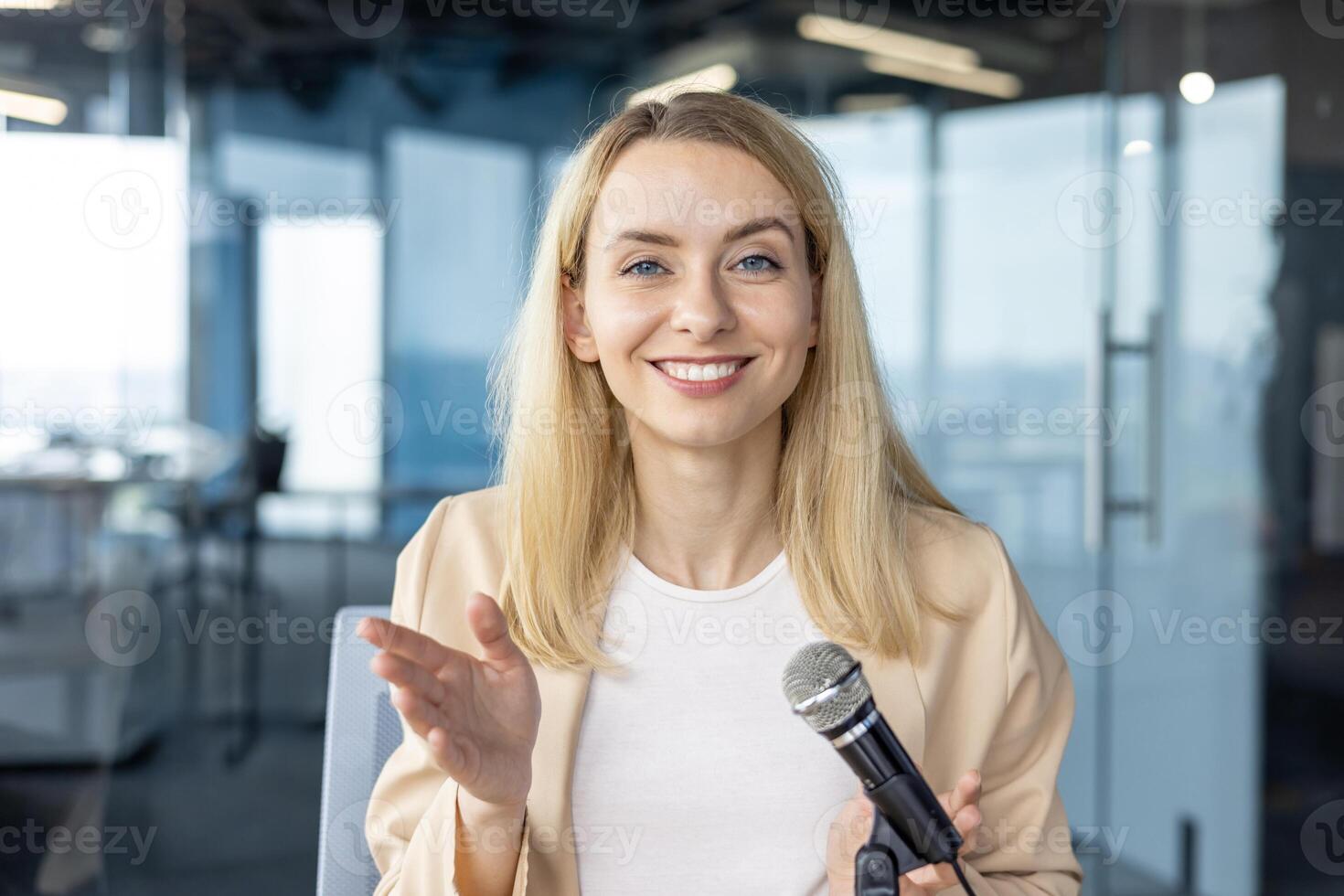 Smiling businesswoman holding a microphone during a presentation in a modern office. Professional woman delivering a speech or lecture. photo