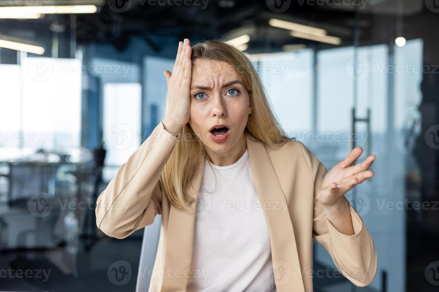 A young businesswoman appears surprised and bewildered in a sleek, modern office setting. Her expression conveys shock and confusion. photo