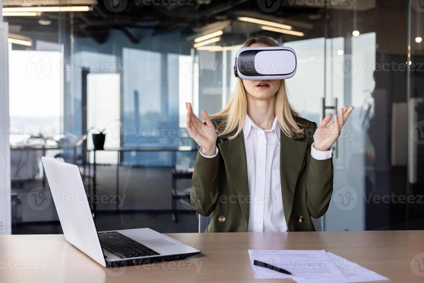 A professional young businesswoman experiences virtual reality with a VR headset in a sleek, modern office setting, surrounded by high-tech ambiance. photo