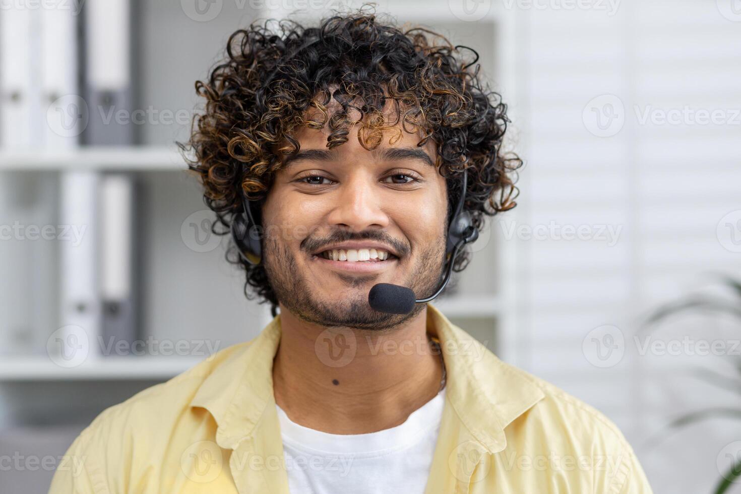 Smiling customer service representative wearing headset, looking at the camera in a modern office setting, ready to assist customers. photo